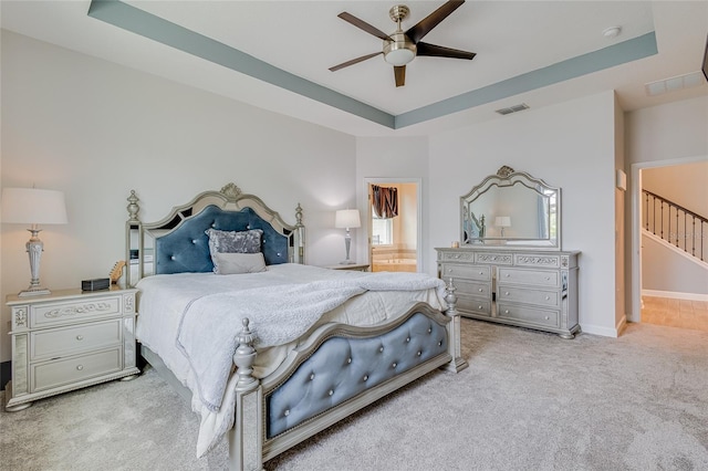 carpeted bedroom with ceiling fan and a raised ceiling