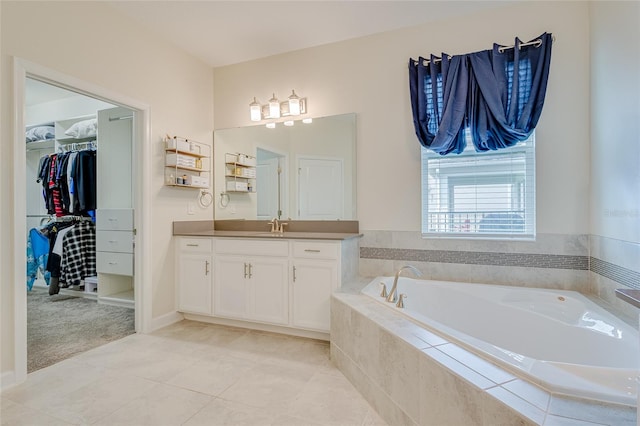 bathroom featuring tile patterned flooring, tiled tub, and vanity