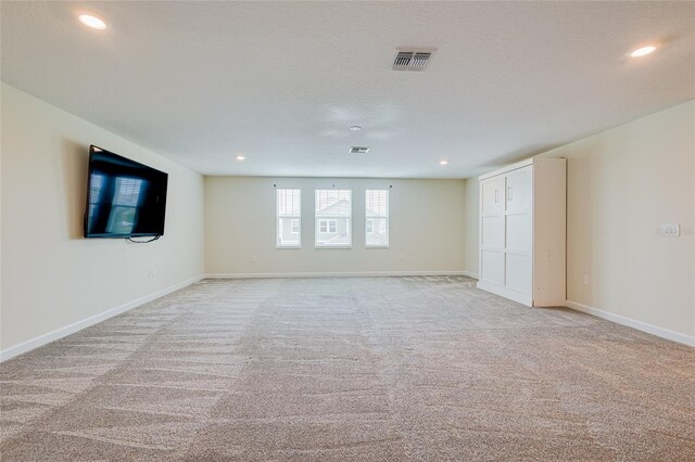 unfurnished room featuring light carpet and a textured ceiling