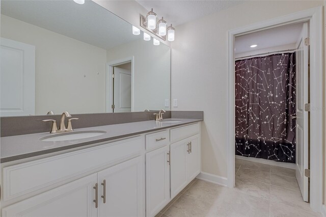 bathroom with tile patterned floors and dual bowl vanity