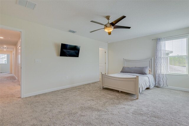 unfurnished bedroom featuring light carpet, multiple windows, and ceiling fan