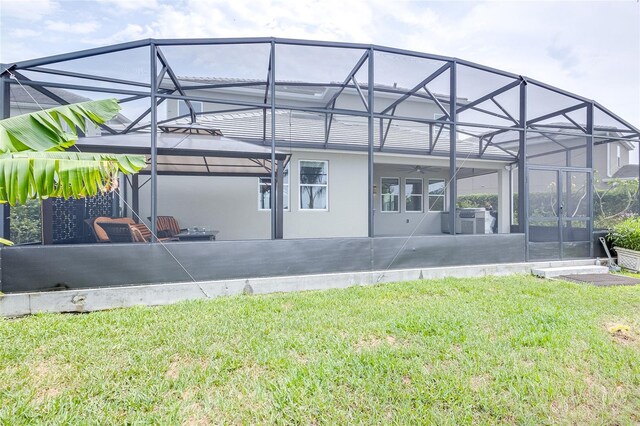 rear view of house with a patio, glass enclosure, and a yard