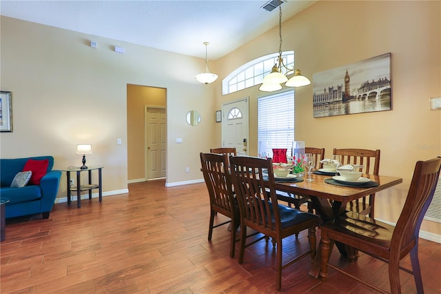 dining space with hardwood / wood-style flooring and a high ceiling