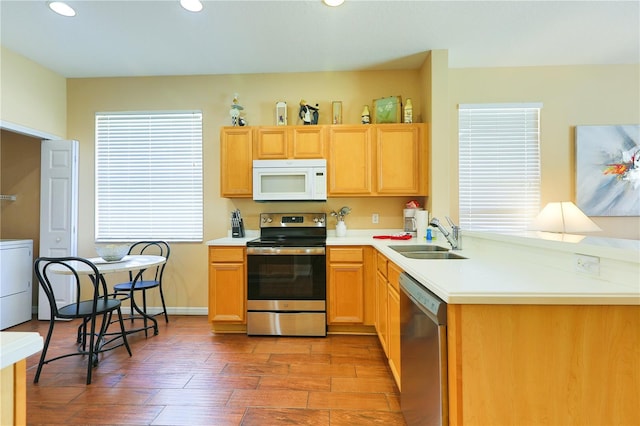 kitchen featuring stainless steel appliances, washer / dryer, sink, and wood-type flooring