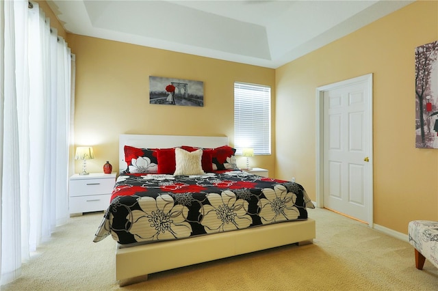 bedroom featuring light colored carpet and a tray ceiling