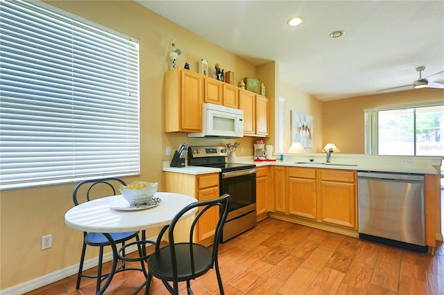 kitchen featuring sink, light hardwood / wood-style flooring, ceiling fan, appliances with stainless steel finishes, and kitchen peninsula