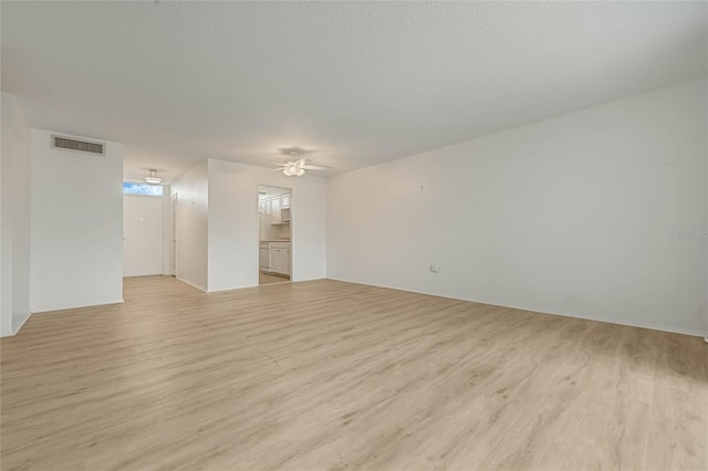 empty room with a textured ceiling, ceiling fan, and light wood-type flooring