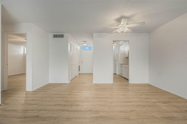 empty room featuring ceiling fan, light hardwood / wood-style flooring, and a textured ceiling