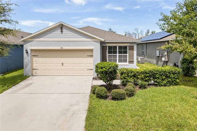 ranch-style home with a garage, solar panels, and a front lawn