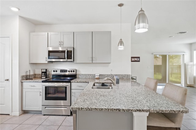 kitchen with a breakfast bar, sink, hanging light fixtures, appliances with stainless steel finishes, and kitchen peninsula