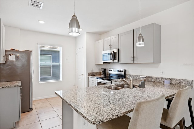 kitchen with hanging light fixtures, appliances with stainless steel finishes, sink, and kitchen peninsula