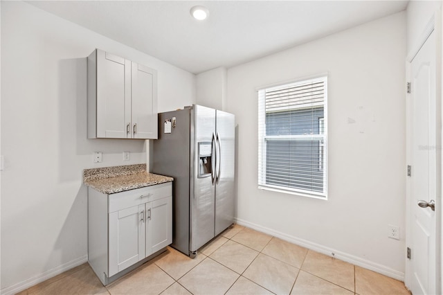 kitchen featuring light tile patterned floors, gray cabinets, light stone countertops, and stainless steel refrigerator with ice dispenser