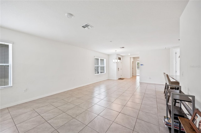 tiled empty room featuring an inviting chandelier