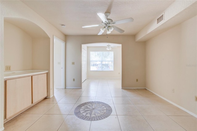 tiled spare room featuring a textured ceiling and ceiling fan