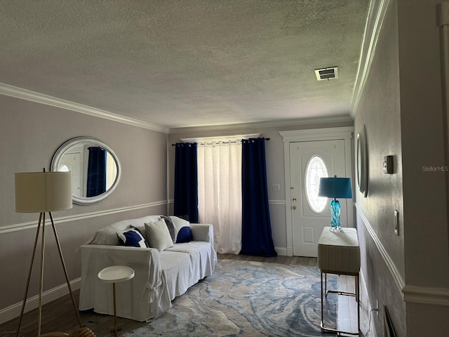 living area featuring a textured ceiling, ornamental molding, wood finished floors, and visible vents