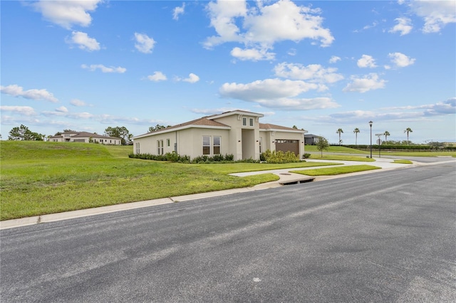 view of front of home with stucco siding, driveway, a front yard, and a garage