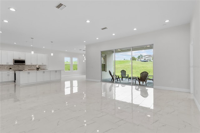 interior space with white cabinetry, stainless steel microwave, plenty of natural light, and marble finish floor