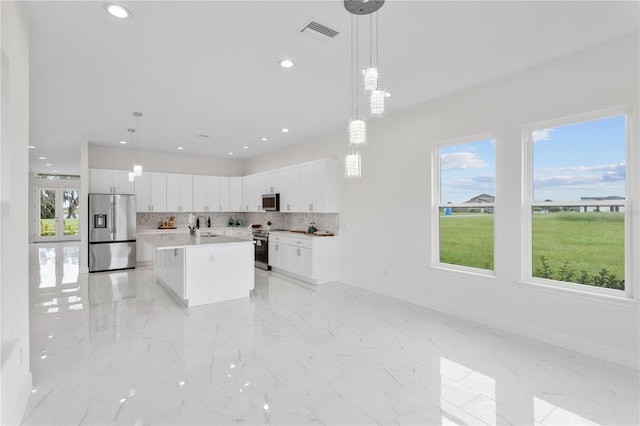 kitchen with a center island, appliances with stainless steel finishes, decorative light fixtures, and white cabinetry