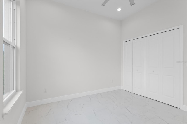 unfurnished bedroom with baseboards, recessed lighting, a closet, multiple windows, and marble finish floor