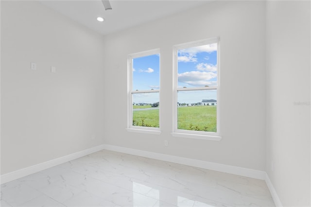 empty room featuring recessed lighting, marble finish floor, and baseboards