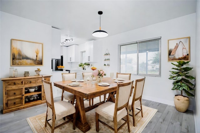 dining room with rail lighting and light hardwood / wood-style flooring