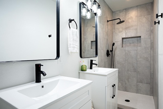 bathroom featuring tiled shower and double sink vanity