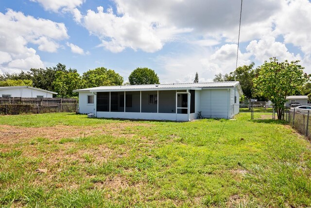 back of property featuring a yard and a sunroom