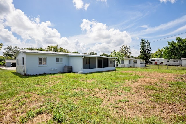 back of property featuring a sunroom, a lawn, and cooling unit