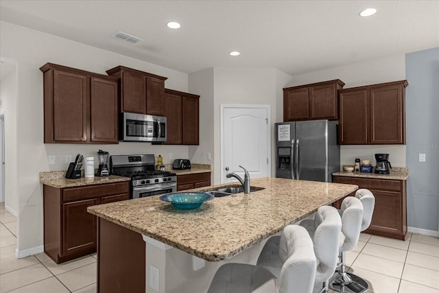 kitchen featuring appliances with stainless steel finishes, a breakfast bar area, sink, and a center island with sink