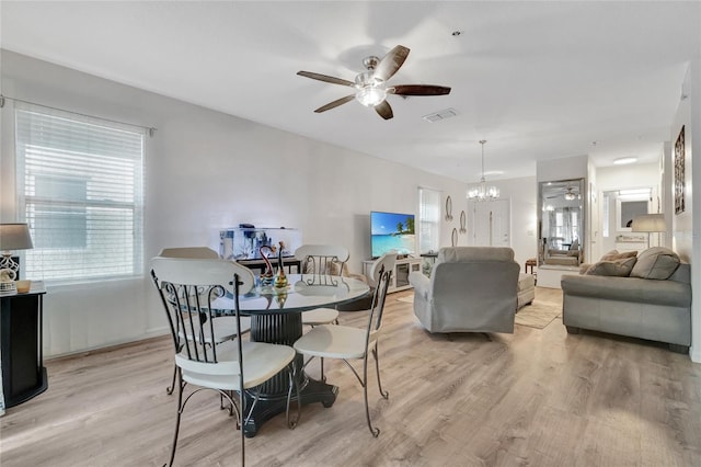 dining room featuring ceiling fan with notable chandelier, light wood-type flooring, and plenty of natural light