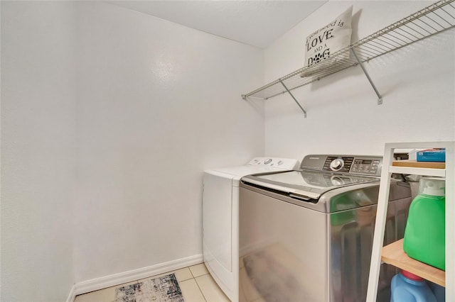 laundry area with washer and dryer and light tile patterned floors