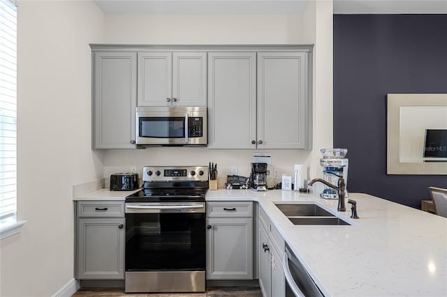 kitchen with gray cabinets, stainless steel appliances, a healthy amount of sunlight, and sink