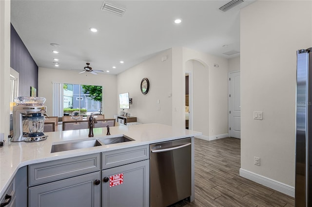 kitchen featuring appliances with stainless steel finishes, gray cabinetry, sink, dark wood-type flooring, and ceiling fan