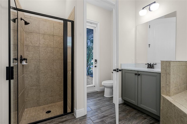 bathroom with hardwood / wood-style floors, a shower with shower door, toilet, and vanity