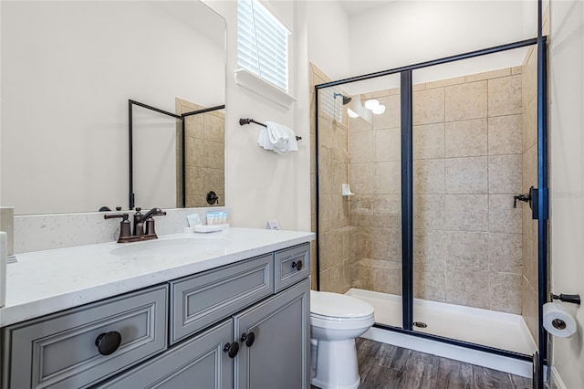 bathroom featuring toilet, hardwood / wood-style floors, vanity, and an enclosed shower