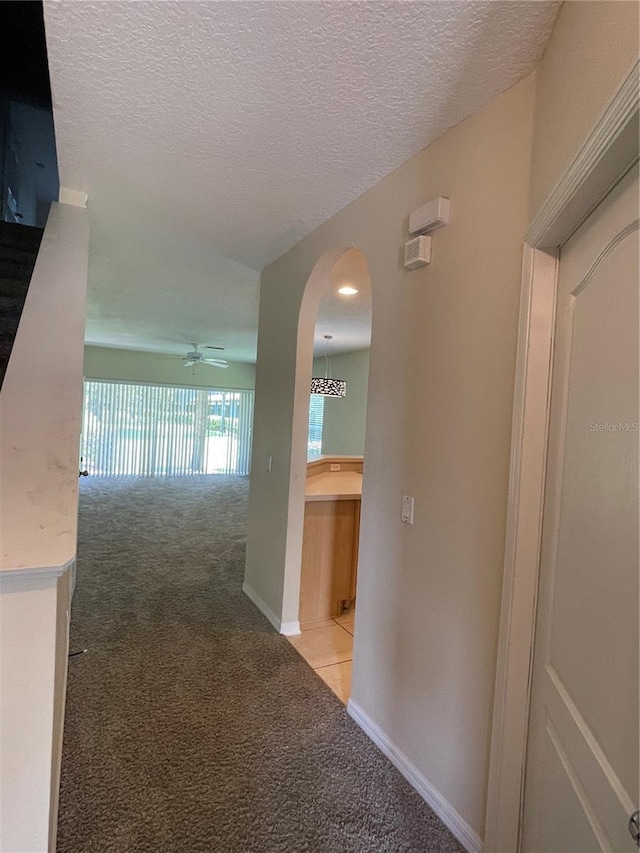 hall with light carpet and a textured ceiling