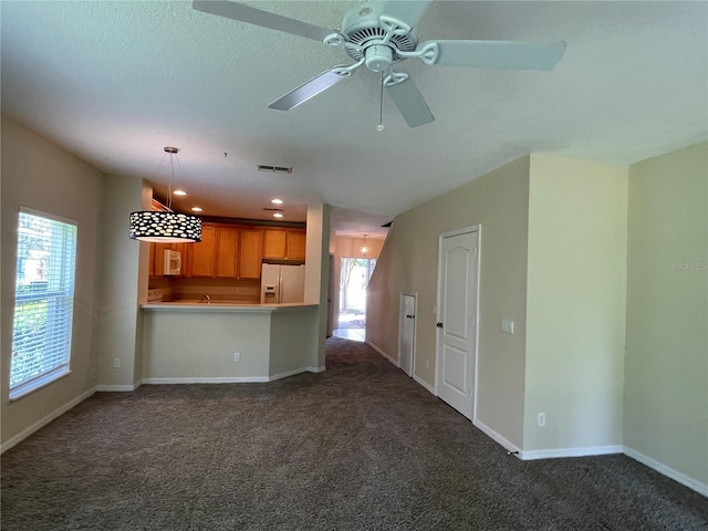 unfurnished living room with ceiling fan, plenty of natural light, and dark carpet