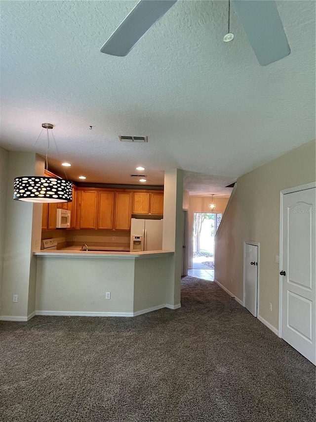 kitchen featuring decorative light fixtures, a textured ceiling, kitchen peninsula, dark carpet, and white appliances