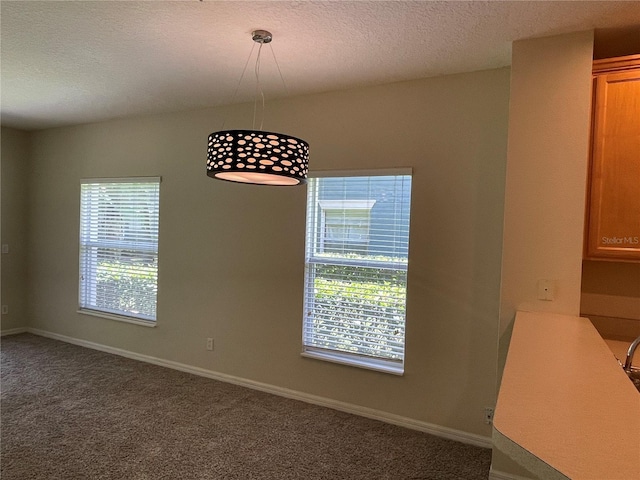 unfurnished dining area featuring dark colored carpet and a textured ceiling