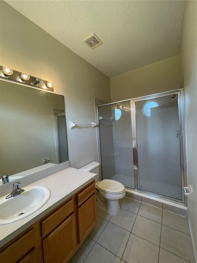 bathroom with tile patterned floors, toilet, a shower with shower door, a textured ceiling, and vanity