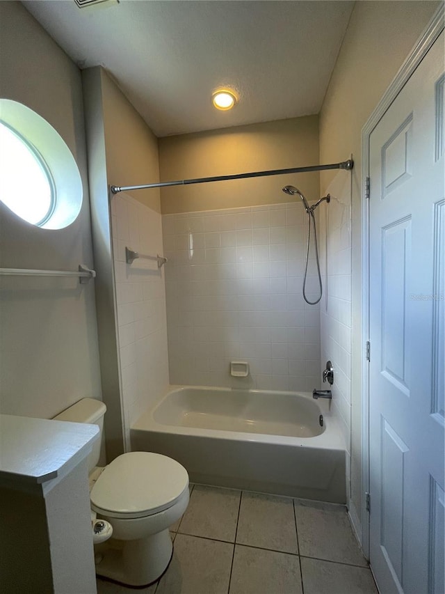 bathroom with tile patterned floors, toilet, and tiled shower / bath combo