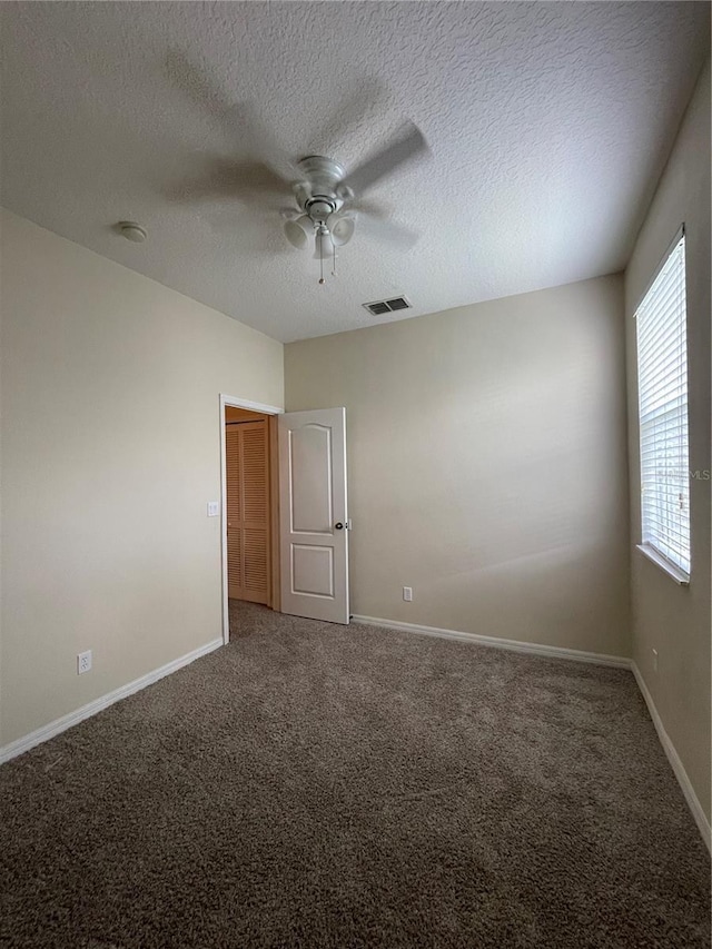 carpeted spare room featuring ceiling fan and a textured ceiling