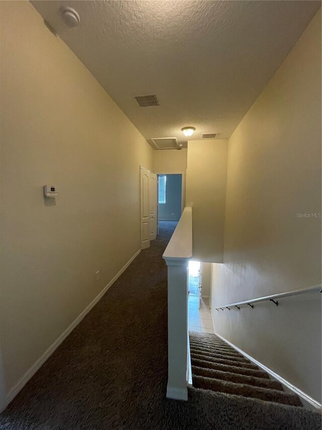 staircase featuring carpet floors and a textured ceiling