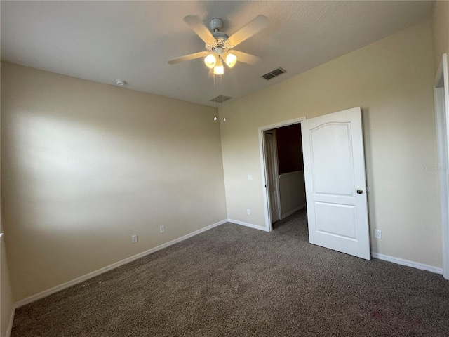 unfurnished bedroom featuring a spacious closet, ceiling fan, and dark colored carpet