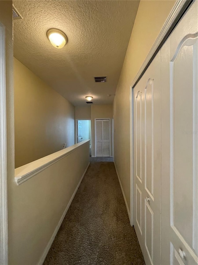 corridor with carpet and a textured ceiling