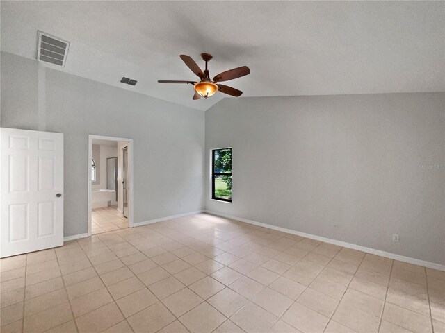 empty room with ceiling fan, light tile patterned floors, and vaulted ceiling