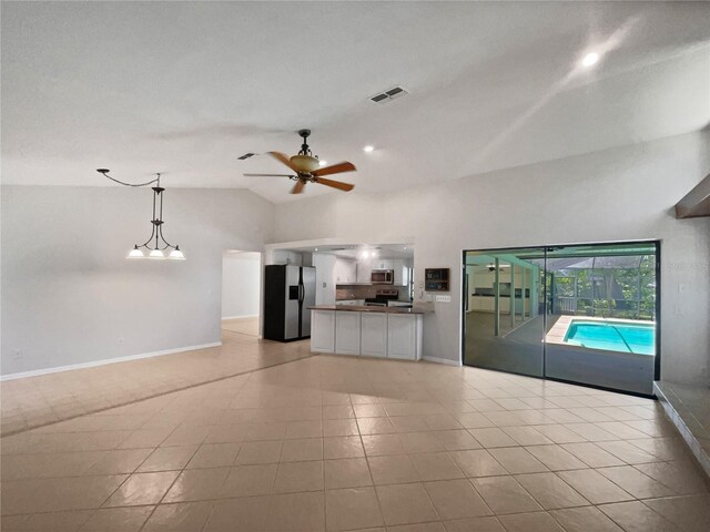 unfurnished living room featuring ceiling fan, light tile patterned floors, and vaulted ceiling