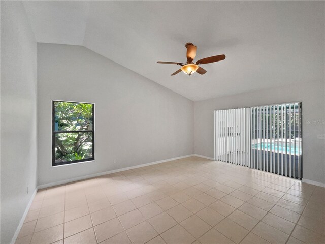 empty room with lofted ceiling, light tile patterned floors, and ceiling fan