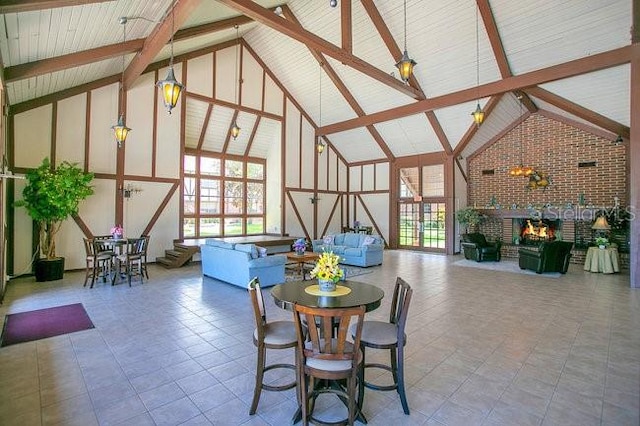 interior space with beam ceiling, a fireplace, high vaulted ceiling, and brick wall