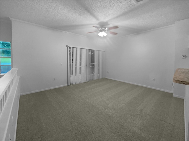 spare room featuring ceiling fan, dark carpet, crown molding, and a textured ceiling